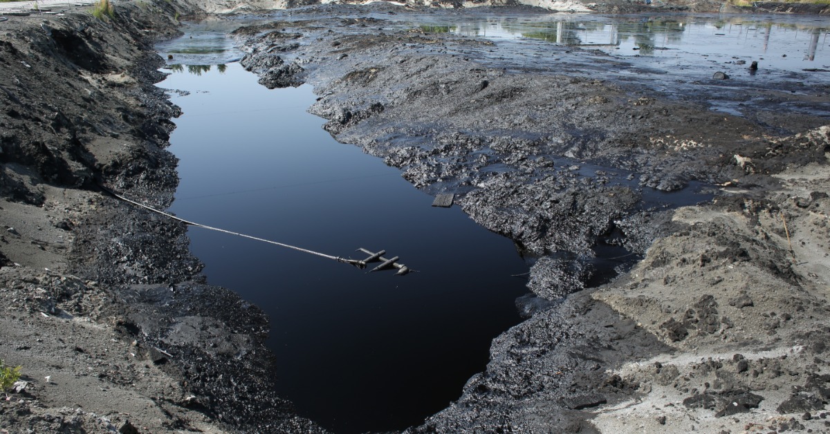 Two large pipes discharge muddy wastewater into a lake, creating foamy currents along the shoreline.